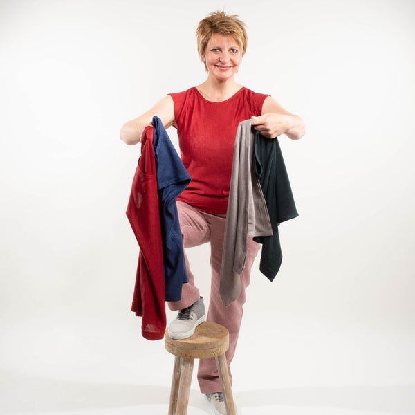 Frau hält viele bunte Leinenshirts im Arm